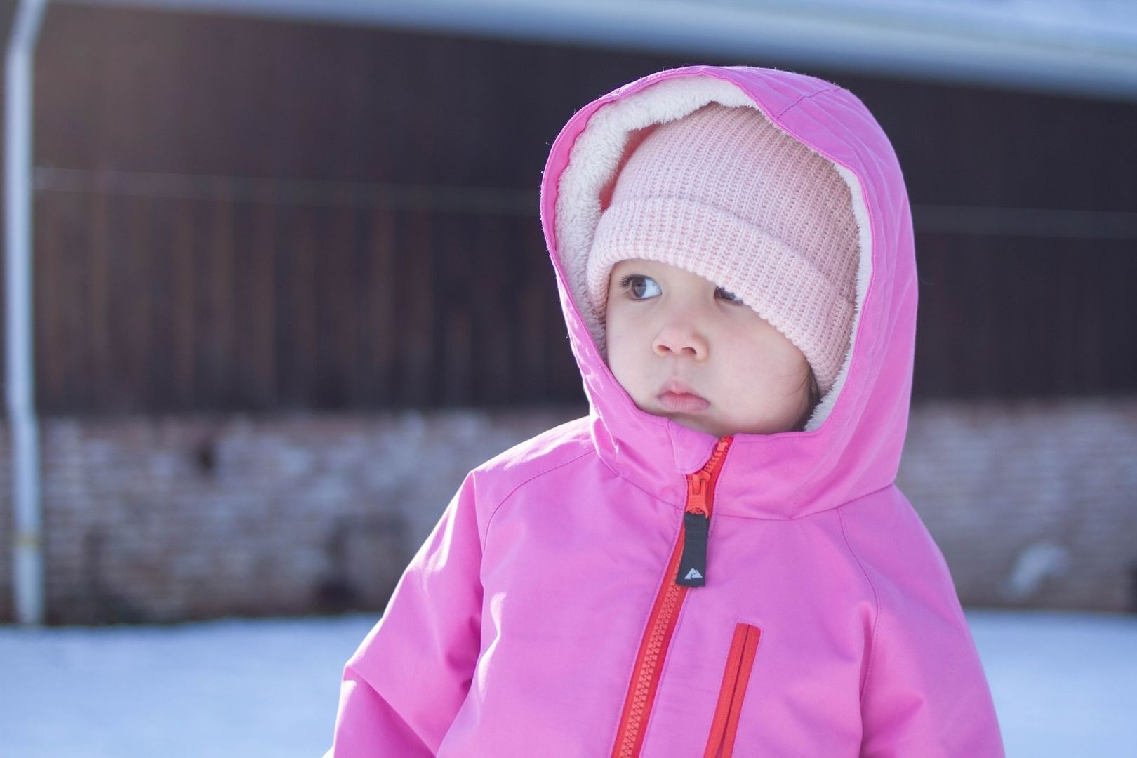 Barn i rosa vinterjacka och stickad mössa utomhus i kyla