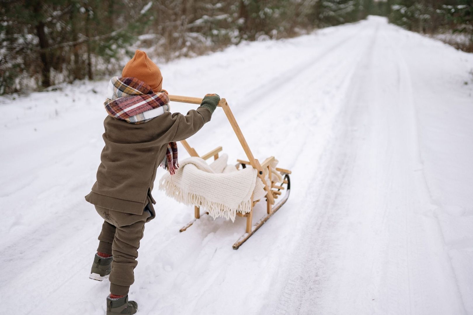 Varmt klätt barn drar en filtklädd träpulka i snön